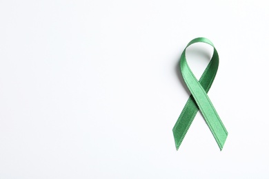 Photo of Green ribbon on white background, top view. Cancer awareness