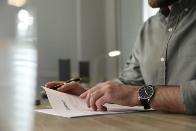 Photo of Businessman working with documents at wooden desk in office, closeup