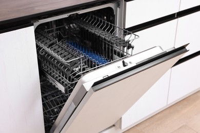 Photo of Built-in dishwasher with open door indoors. Home appliance