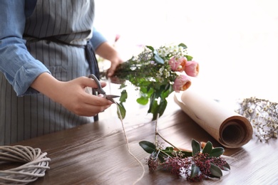 Photo of Female florist creating beautiful bouquet at table