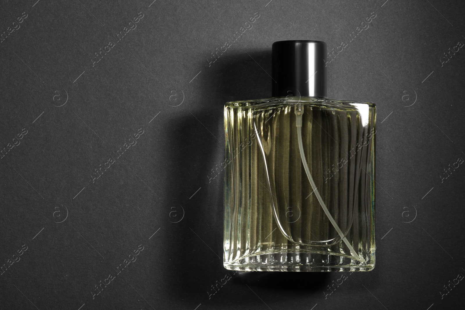 Photo of Luxury men`s perfume in bottle on black background, top view. Space for text