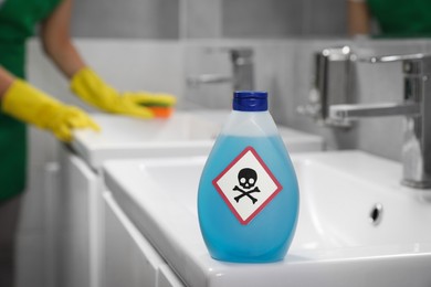 Photo of Bottle of toxic household chemical with warning sign in bathroom
