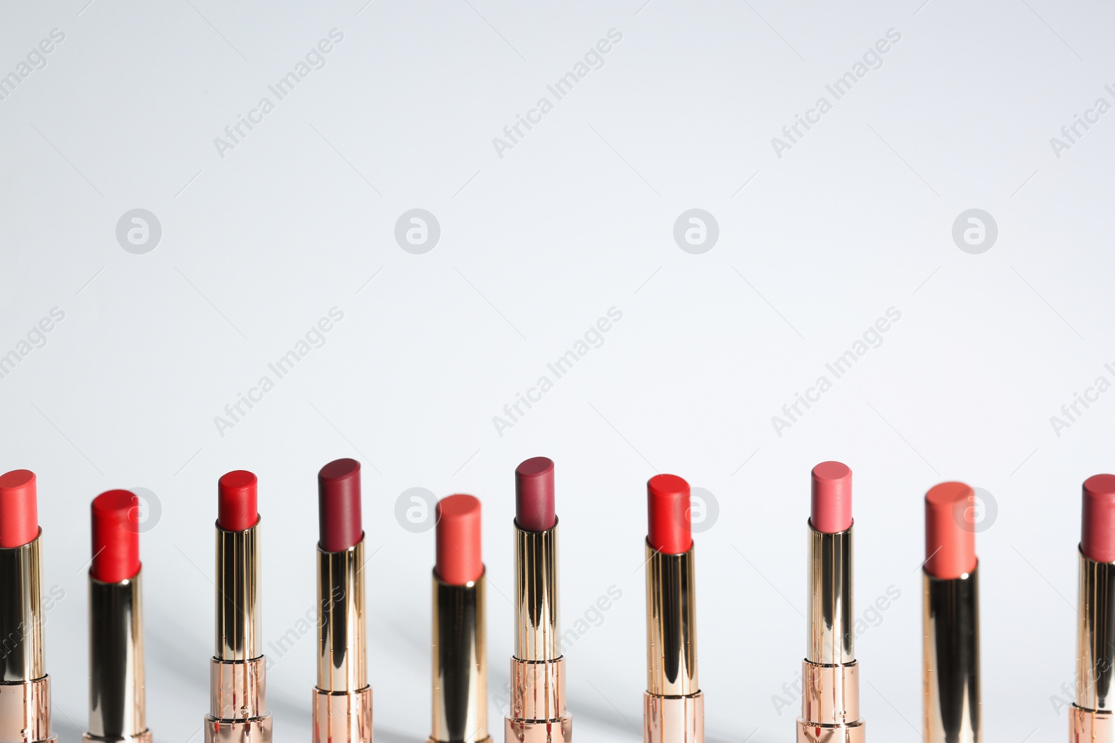 Photo of Set of bright lipsticks in gold tubes on white background