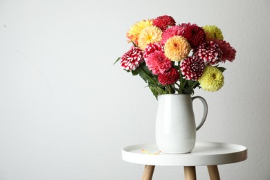 Bouquet of beautiful dahlia flowers on table near white wall. Space for text