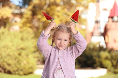 Photo of Cute little girl with tasty candies outdoors