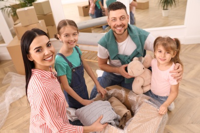 Photo of Happy family unpacking moving box in new house
