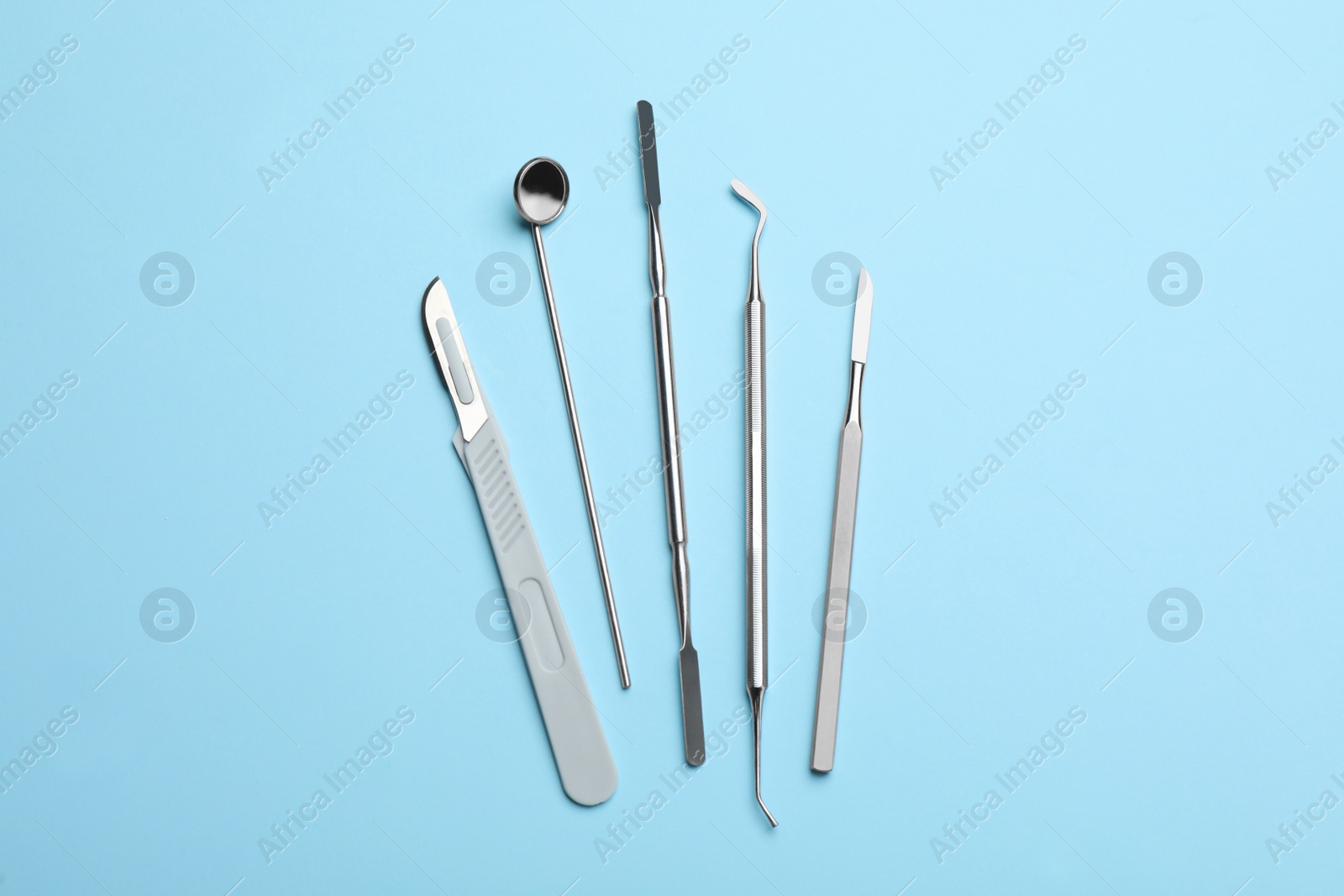 Photo of Set of different dentist's tools on light blue background, flat lay