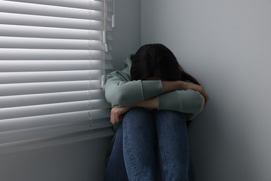 Photo of Sadness. Unhappy woman near window at home