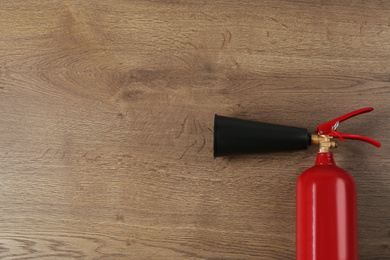 Fire extinguisher on wooden background, top view. Space for text