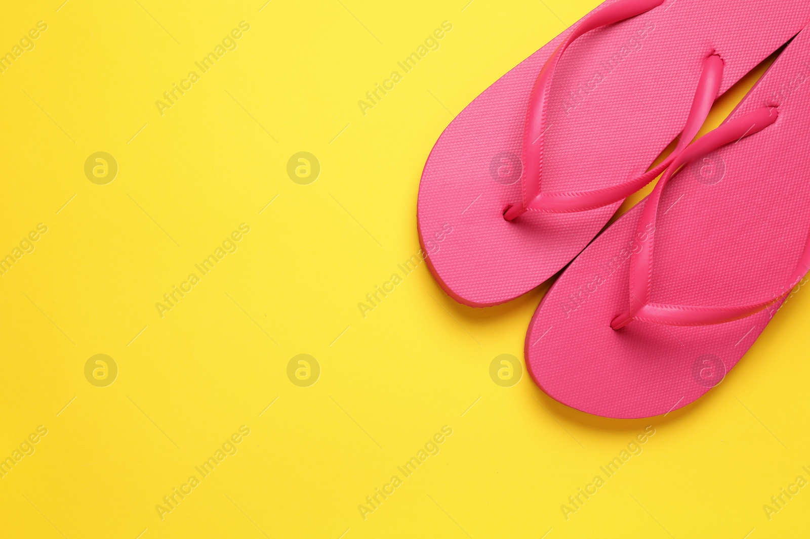 Photo of Stylish pink flip flops on yellow background, top view. Space for text