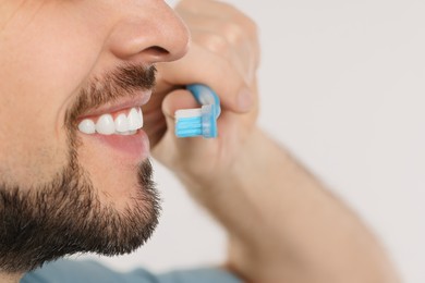 Photo of Man brushing his teeth with plastic toothbrush on white background, closeup