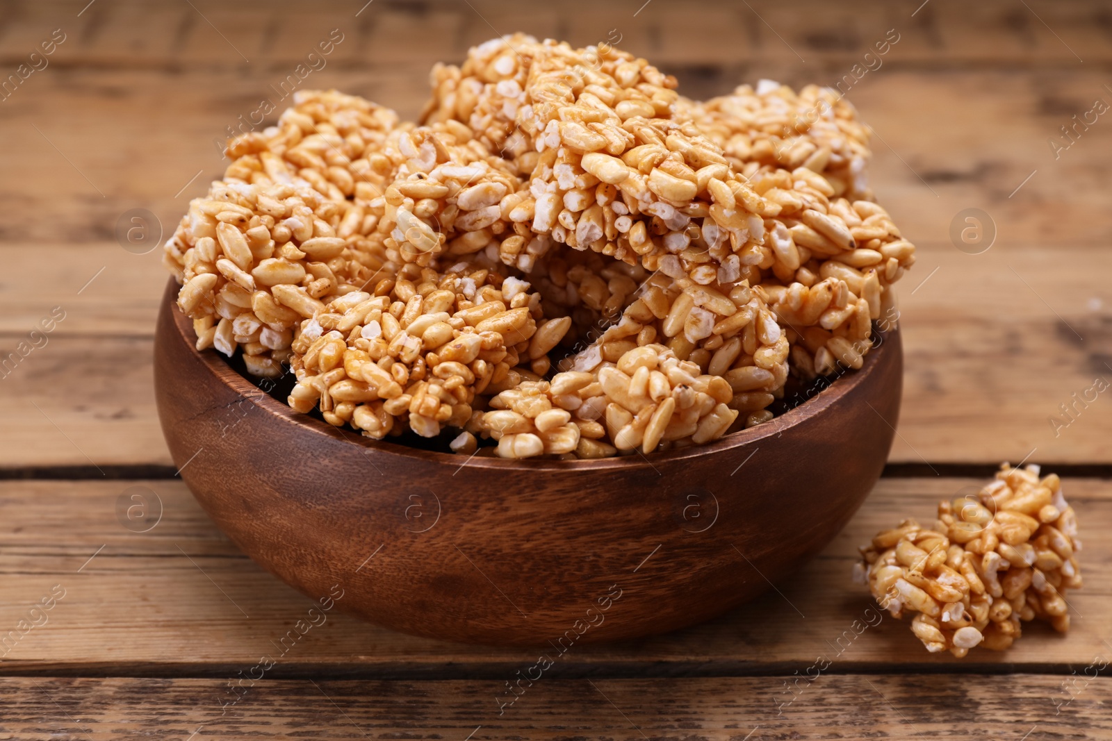 Photo of Bowl of puffed rice pieces (kozinaki) on wooden table, closeup