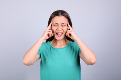 Portrait of stressed young woman on light background