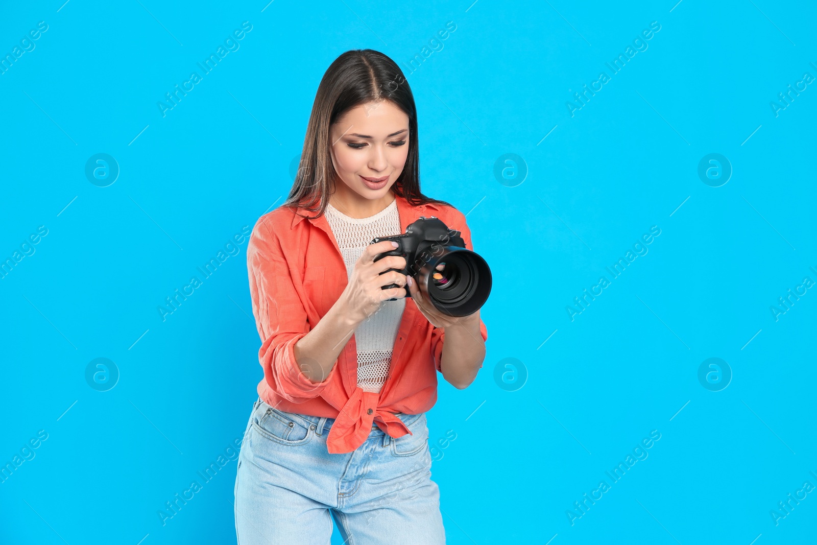Photo of Professional photographer working on light blue background in studio. Space for text