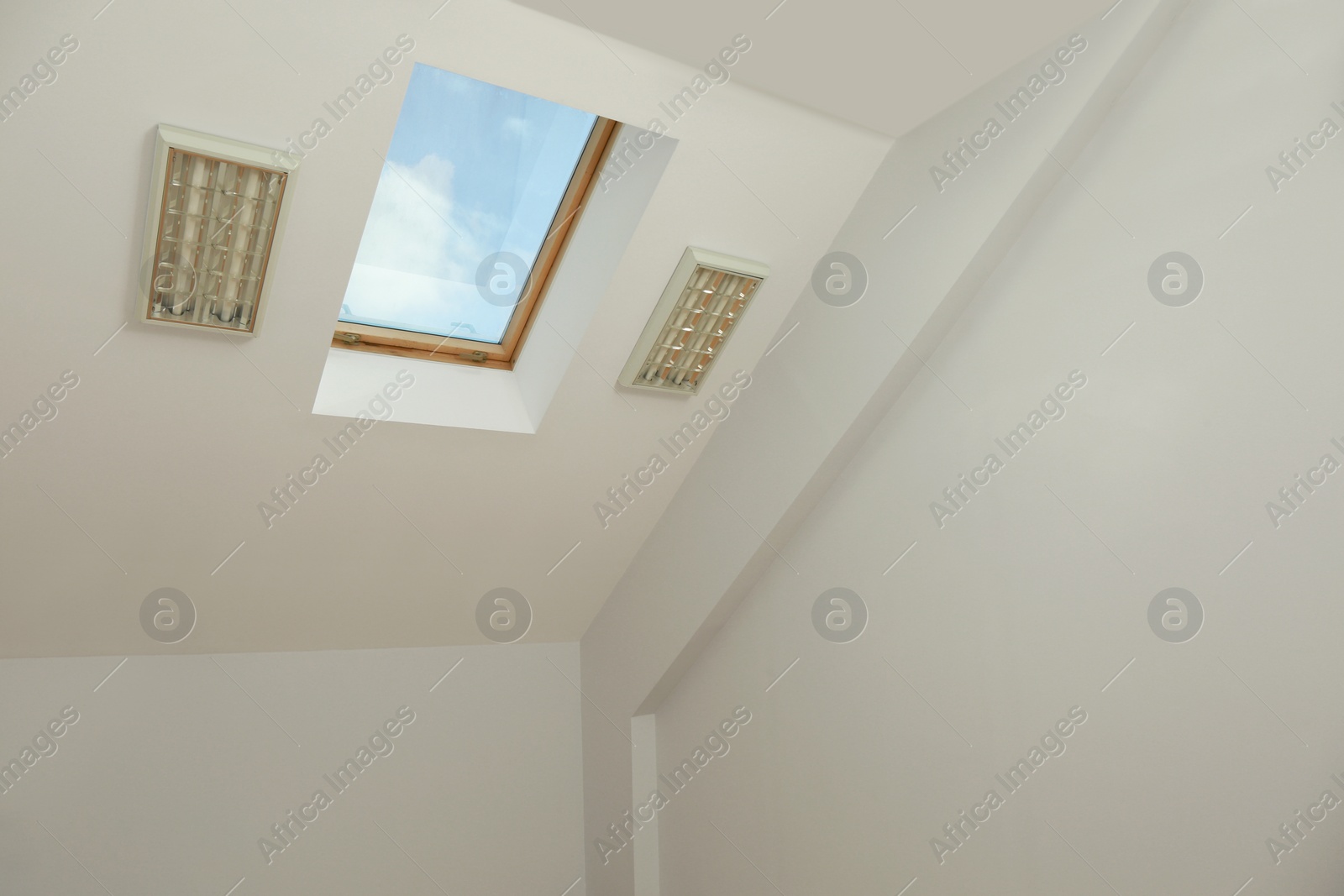 Photo of Skylight roof window on slanted ceiling in attic room, low angle view