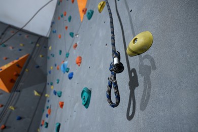 Photo of Climbing rope and wall with holds in gym