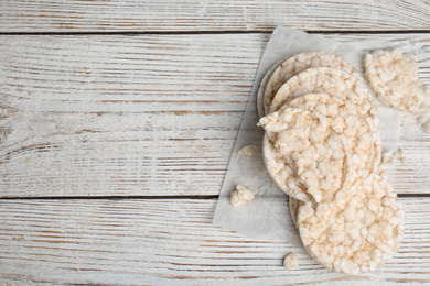 Photo of Puffed rice cakes on white wooden table, flat lay. Space for text