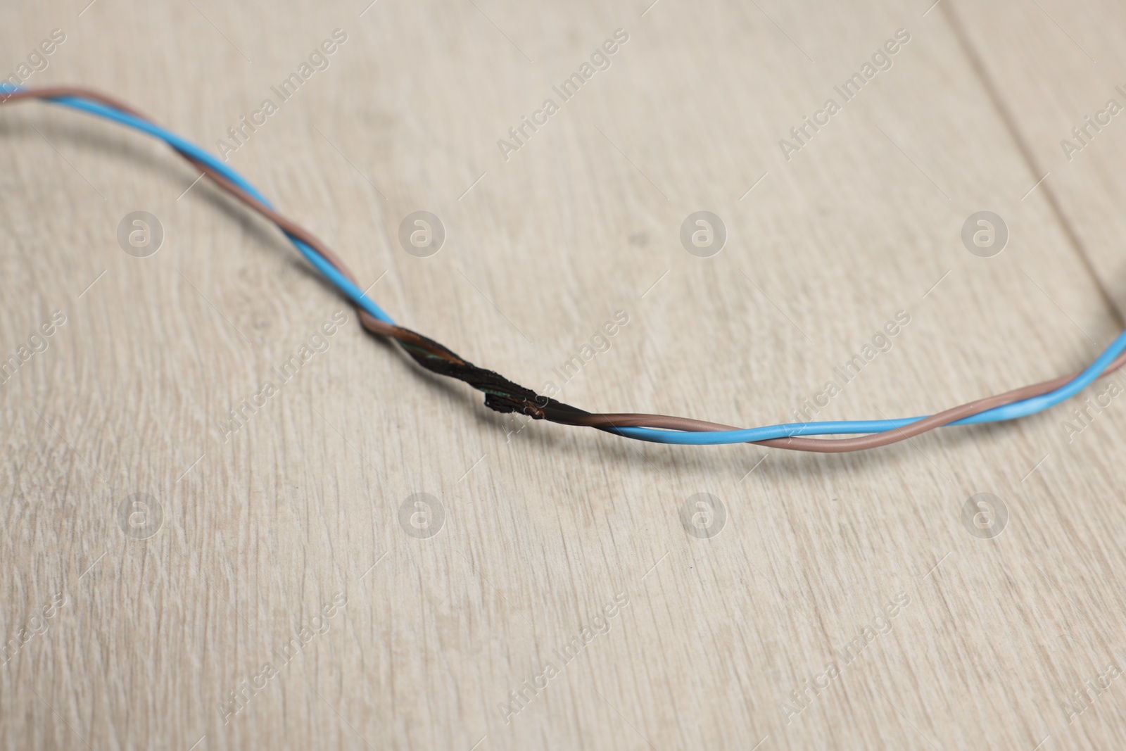 Photo of Burnt wires on wooden floor, closeup. Electrical short circuit