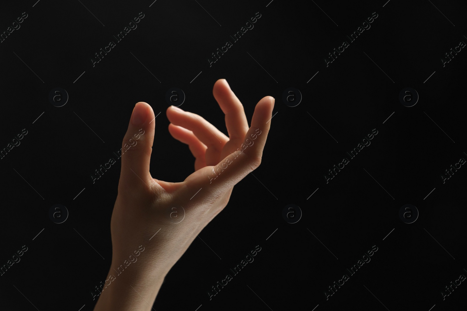 Photo of Woman holding something in hand on black background, closeup. Space for text