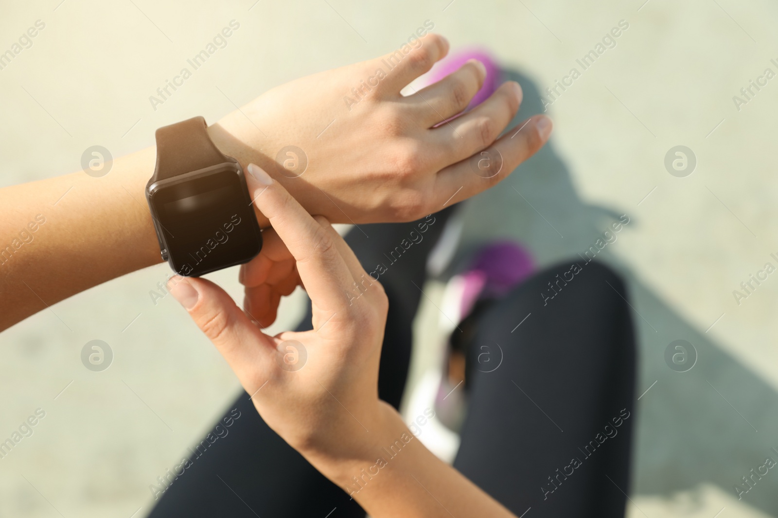 Photo of Woman wearing modern smart watch during training outdoors, above view