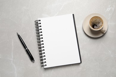 Photo of Open blank notebook, pen and coffee on light grey marble table, flat lay