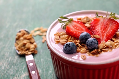 Photo of Bowl with tasty yogurt, berries and granola on table, closeup