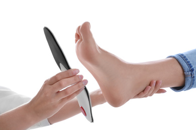 Orthopedist fitting insole on patient's foot against white background, closeup