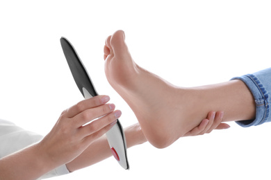 Photo of Orthopedist fitting insole on patient's foot against white background, closeup