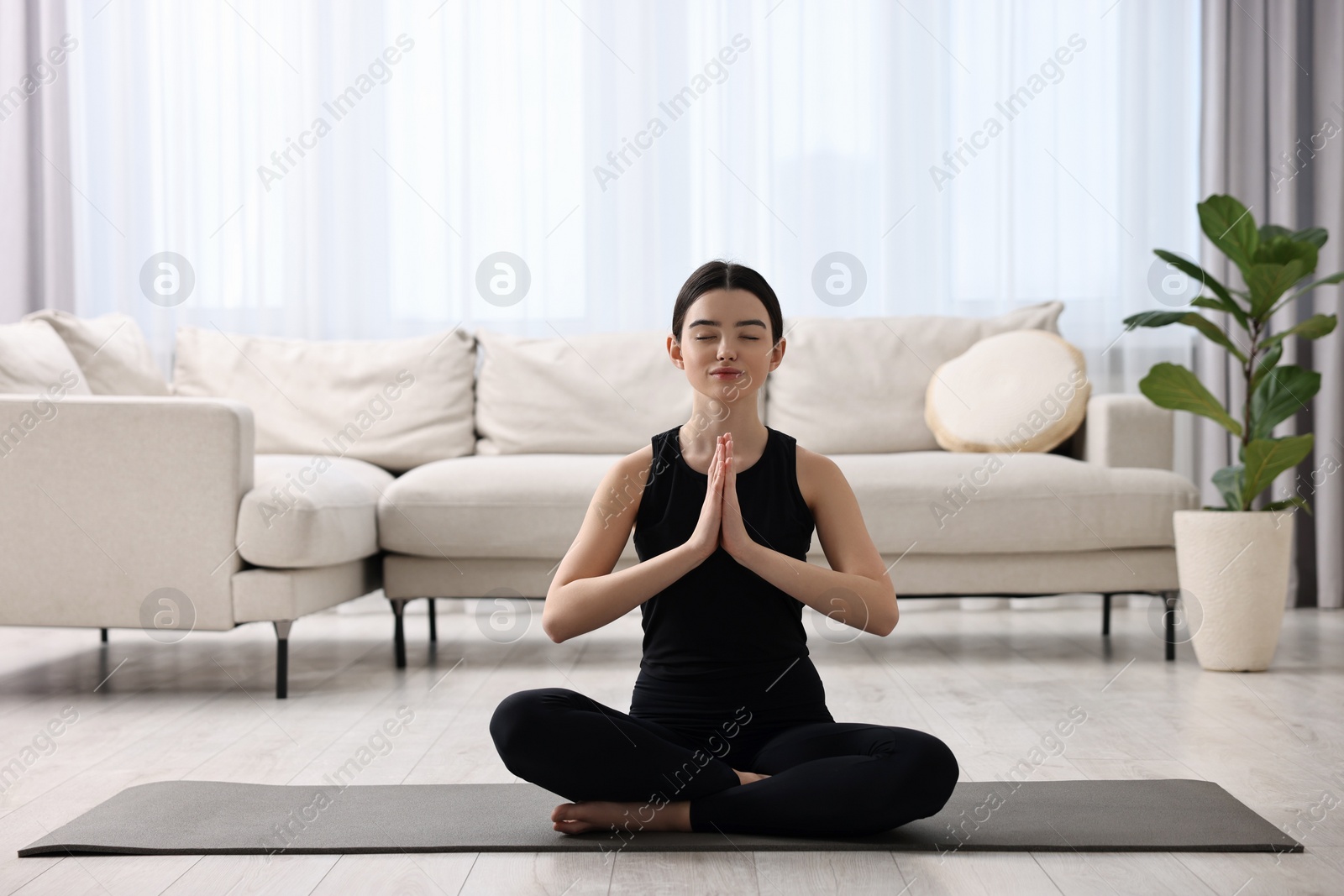 Photo of Beautiful girl meditating on yoga mat at home
