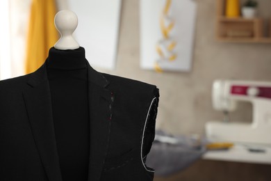 Photo of Mannequin with unfinished suit jacket in tailor shop, closeup. Space for text
