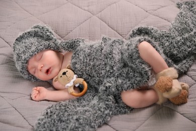 Photo of Cute newborn baby sleeping with teething toy in bed