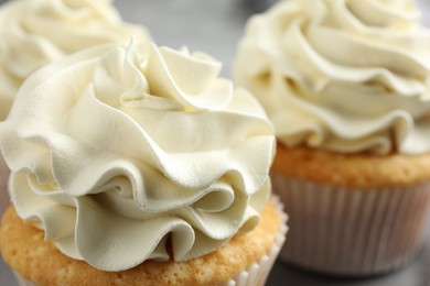 Photo of Tasty cupcakes with vanilla cream on table, closeup