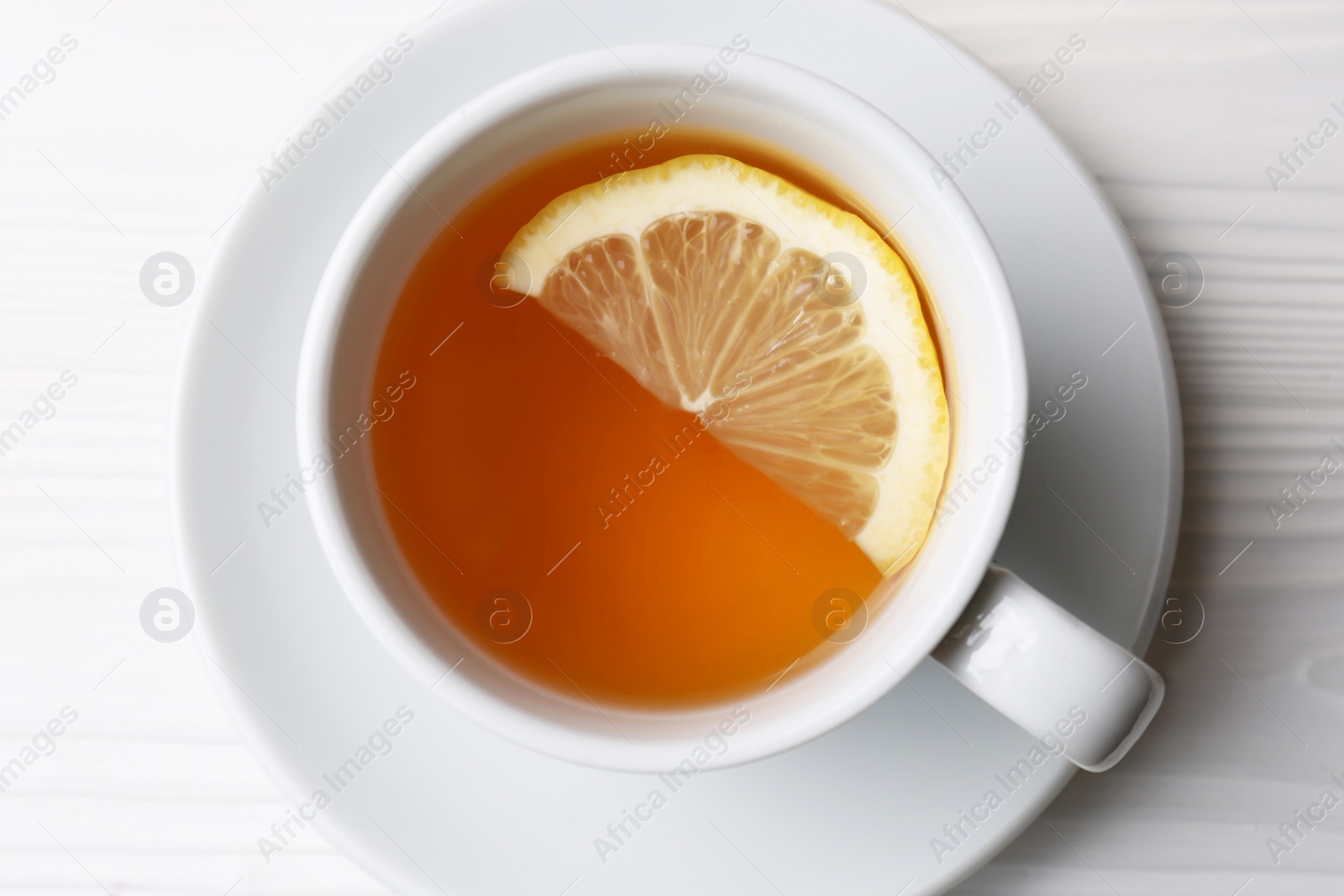 Photo of Cup with delicious immunity boosting tea and lemon on white wooden table, top view