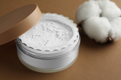 Rice loose face powder and cotton flower on brown background, closeup. Makeup product