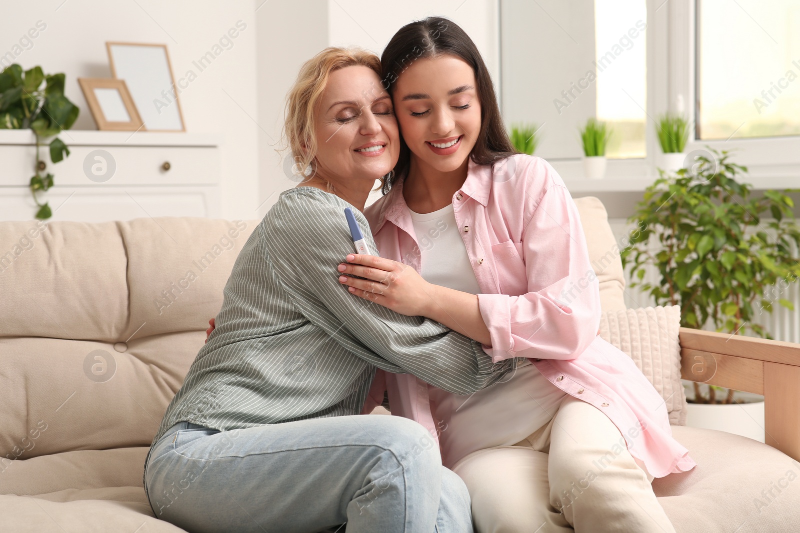 Photo of Happy pregnant woman spending time with her mother at home. Grandparents' reaction to future grandson