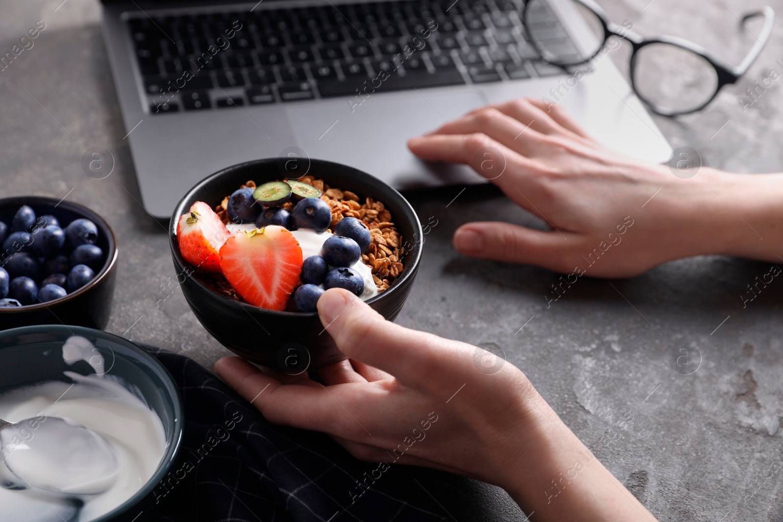 Photo of Woman with tasty granola at workplace, closeup