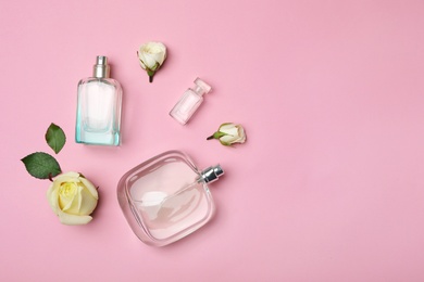 Photo of Bottles of perfume and roses on color background, top view