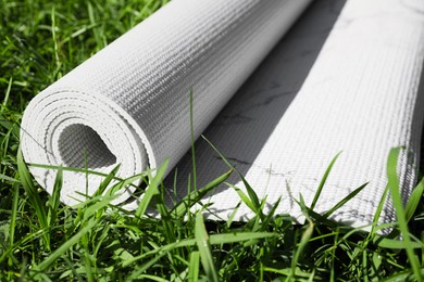 Photo of Karemat or fitness mat on green grass outdoors, closeup