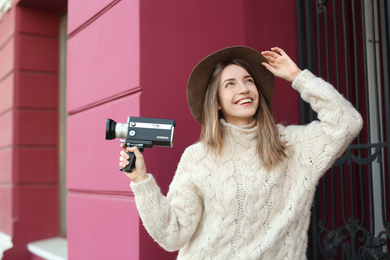 Beautiful young woman with vintage video camera on city street