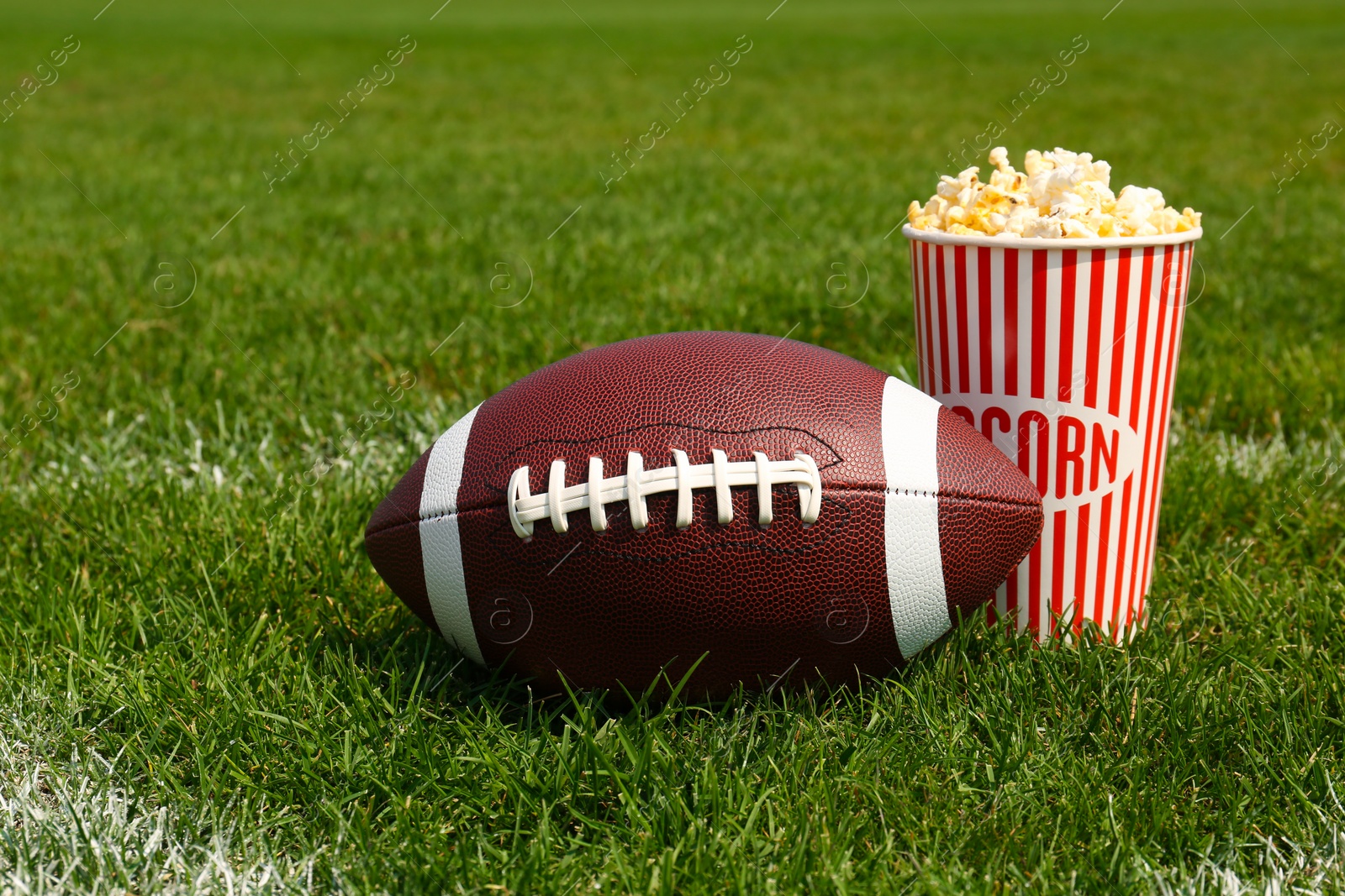 Photo of American football ball with popcorn on green field grass outdoors