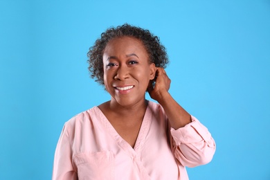 Photo of Portrait of happy African-American woman on light blue background