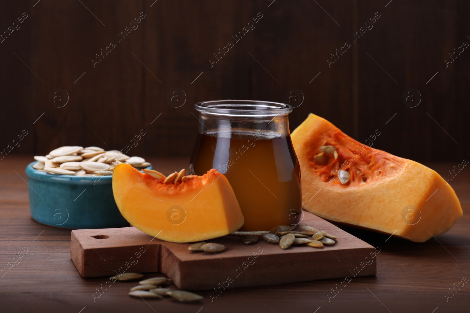 Photo of Fresh pumpkin seed oil in glass jar on wooden table