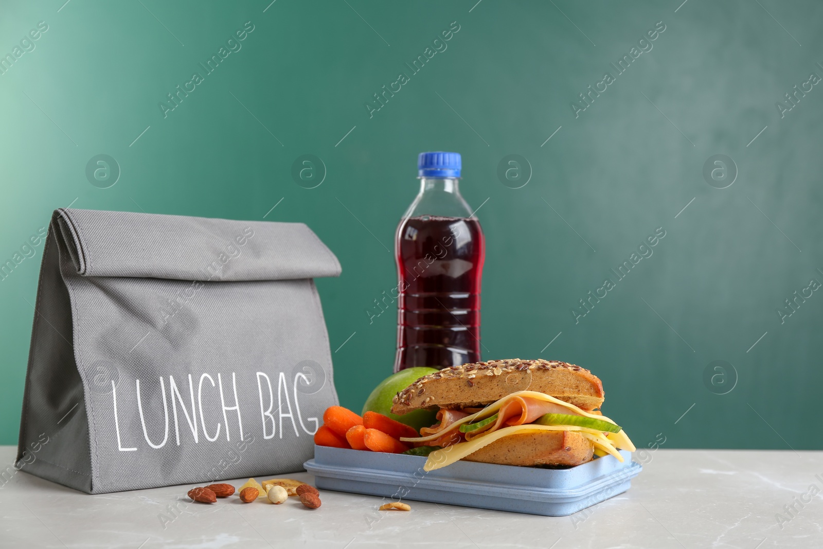 Photo of Lunch box with appetizing food and bag on table against chalkboard