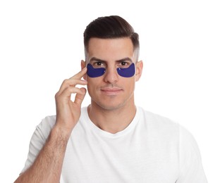 Man applying blue under eye patch on white background