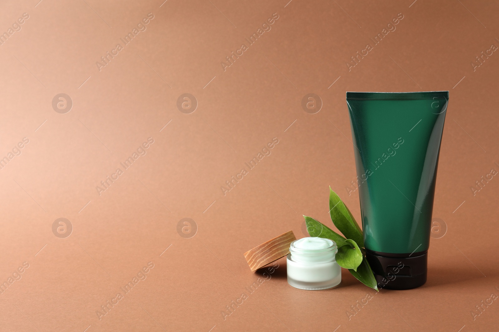 Photo of Tube and jar of men's facial cream on orange background. Space for text