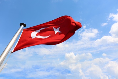 Photo of National Turkish flag fluttering against blue sky 