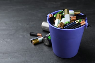 Image of Used batteries and bucket on black table, space for text