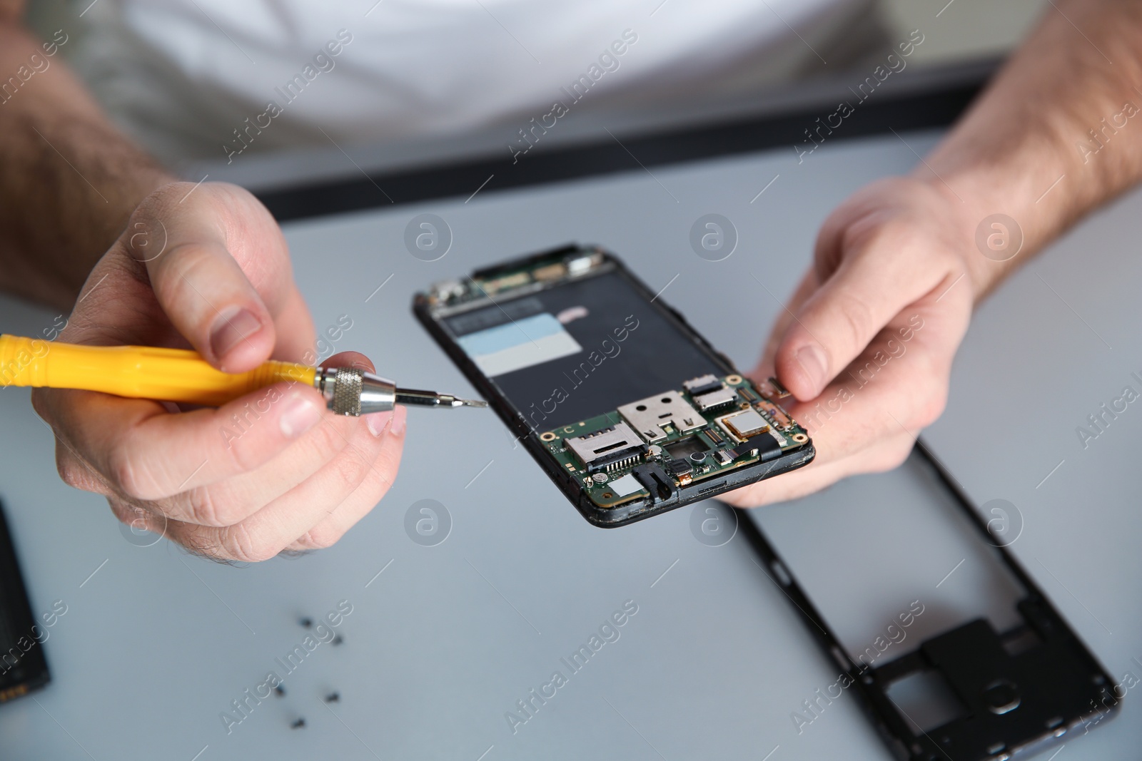 Photo of Technician repairing mobile phone at table, closeup