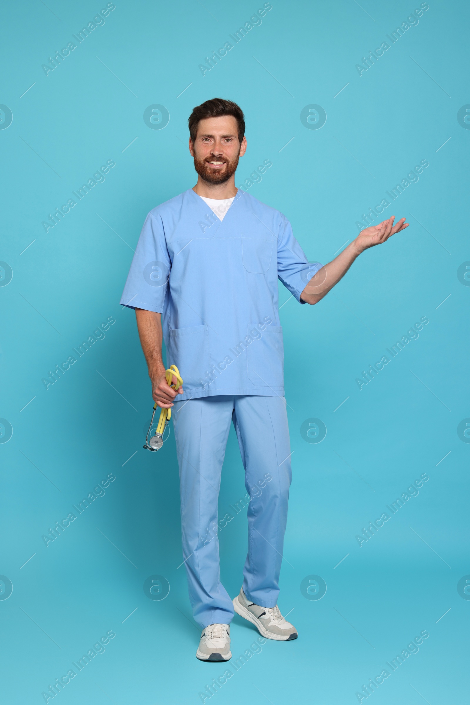 Photo of Full length portrait of doctor with stethoscope on light blue background