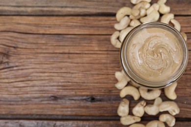 Photo of Tasty cashew nut paste in jar on wooden table, top view. Space for text